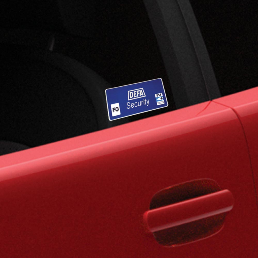 Nærbilde av DEFA alarm vindusdekal på rød bil