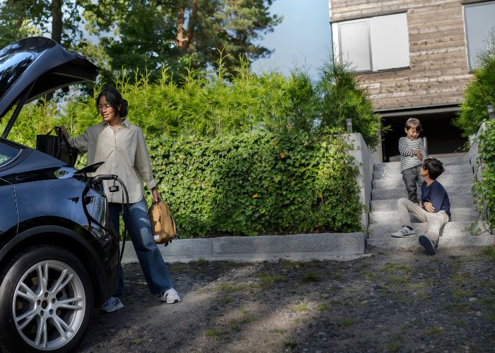 woman and kids with a charging electric car