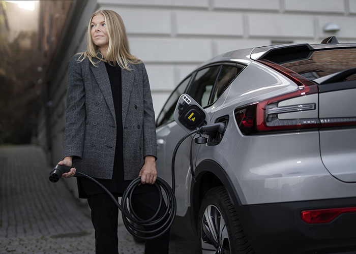 Woman holding black eConnect charging cable connected to electric vehicle
