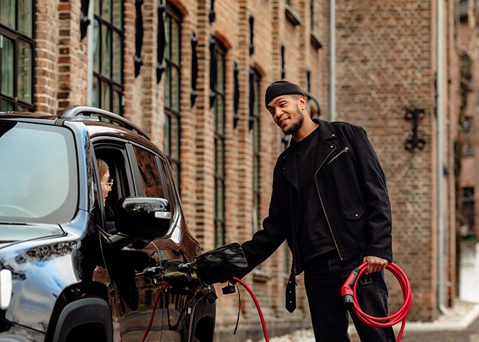 Man connecting red eConnect charging cable to car in the city