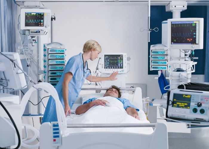Sykepleier overvåker overvåker skjerm over sovende pasient