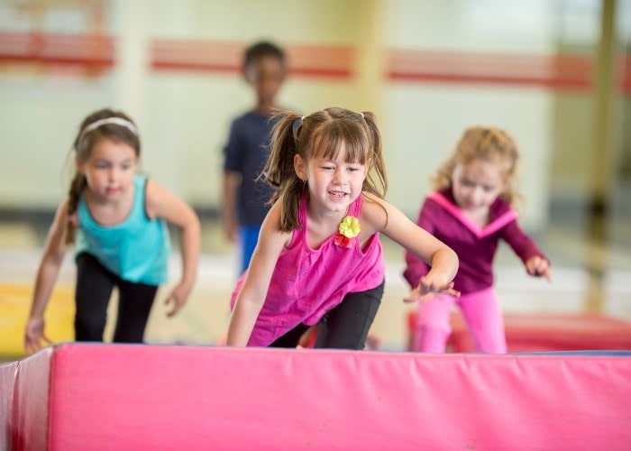 Girls running over mat in school gym