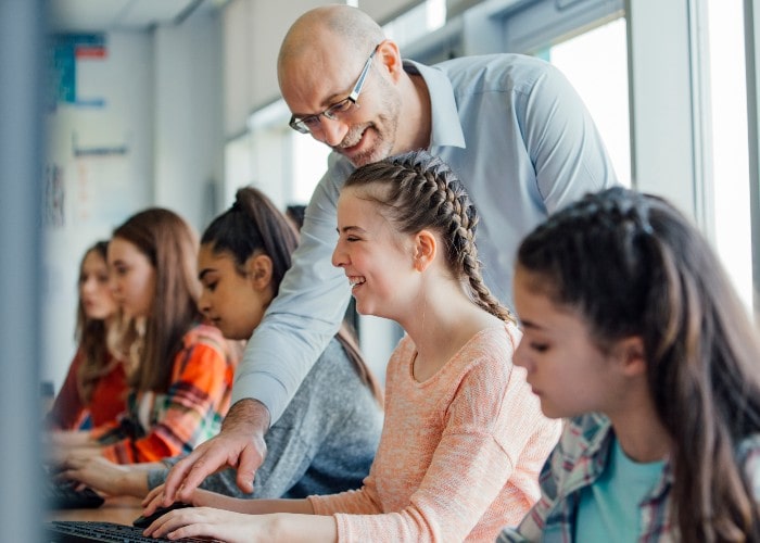 Smiling teacher helping teenage student