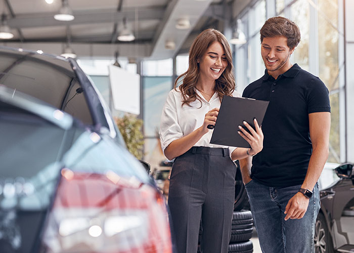 Couple in a car dealership reviewing features