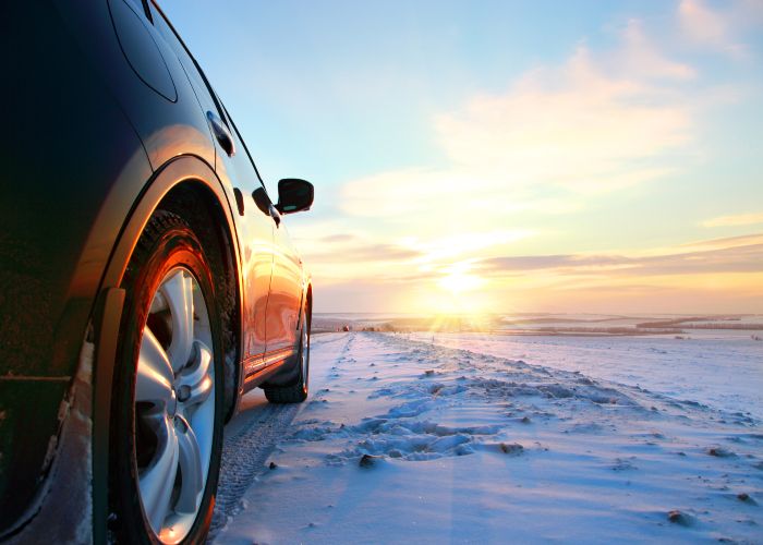 Car on winter road in sunrise