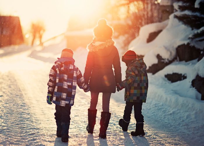 Children holding hands in sunset on winter road