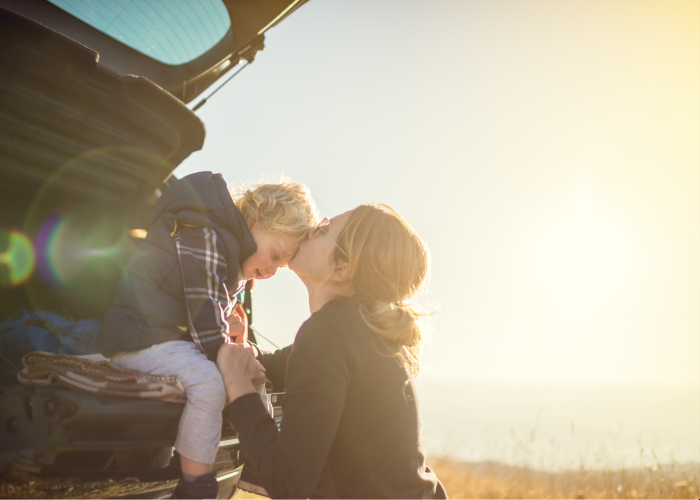 Woman kissing her son on the forehead winter car